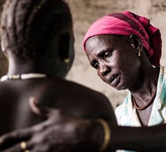 Pregnant woman being helped by midwife Red Cross